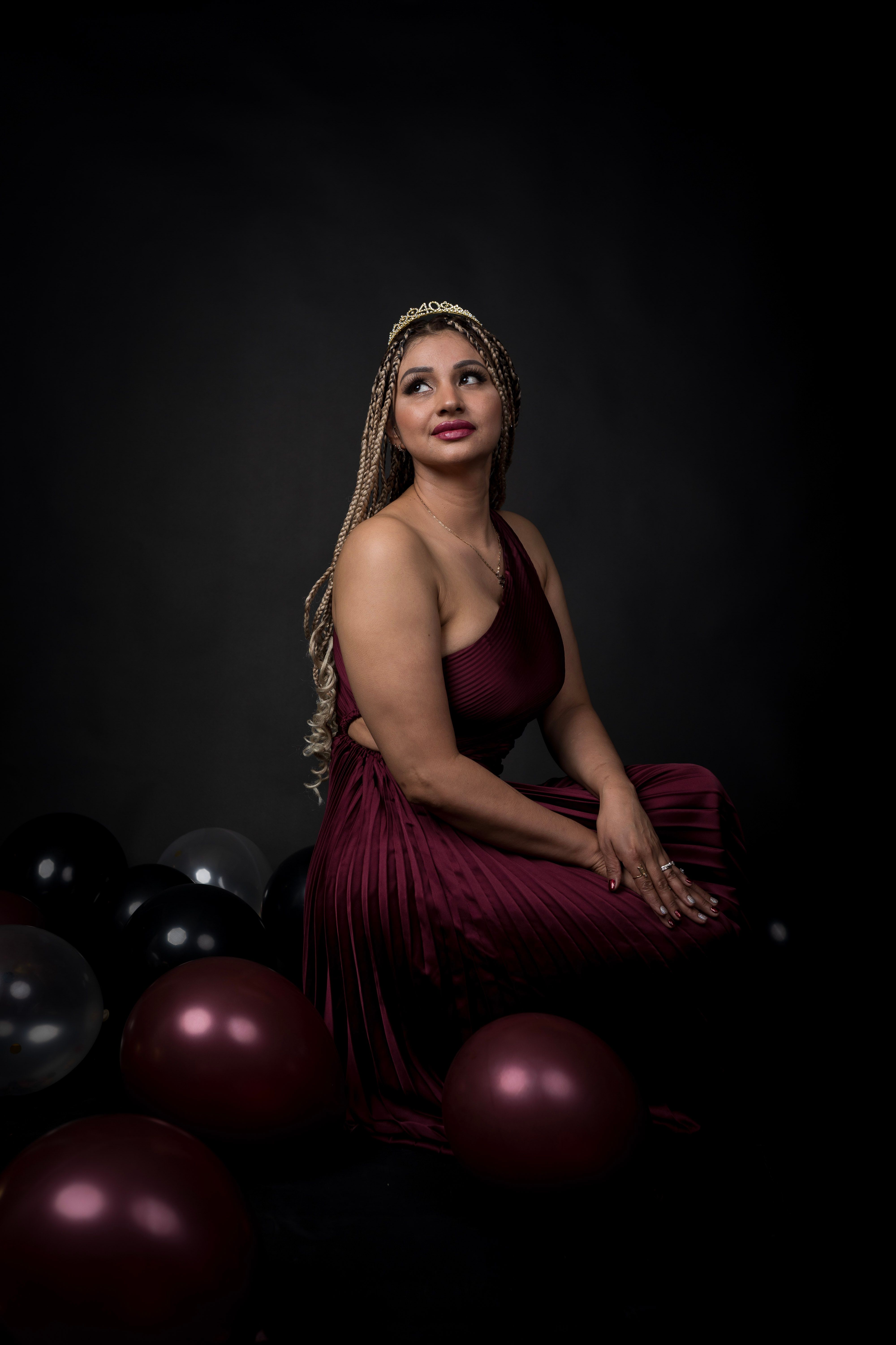 Woman posing in a polished milestone portrait beside balloons.